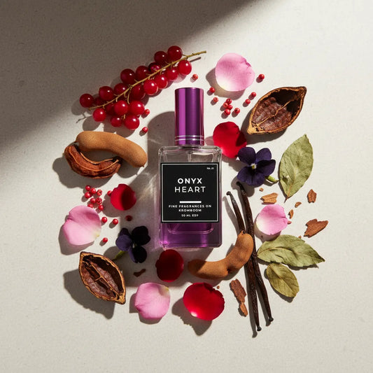 Perfume bottle labeled 'Onyx Heart' surrounded by red berries, flowers, and leaves on a light background