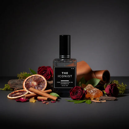 Perfume bottle labeled 'The Iconist' surrounded by flowers and spices on a dark background