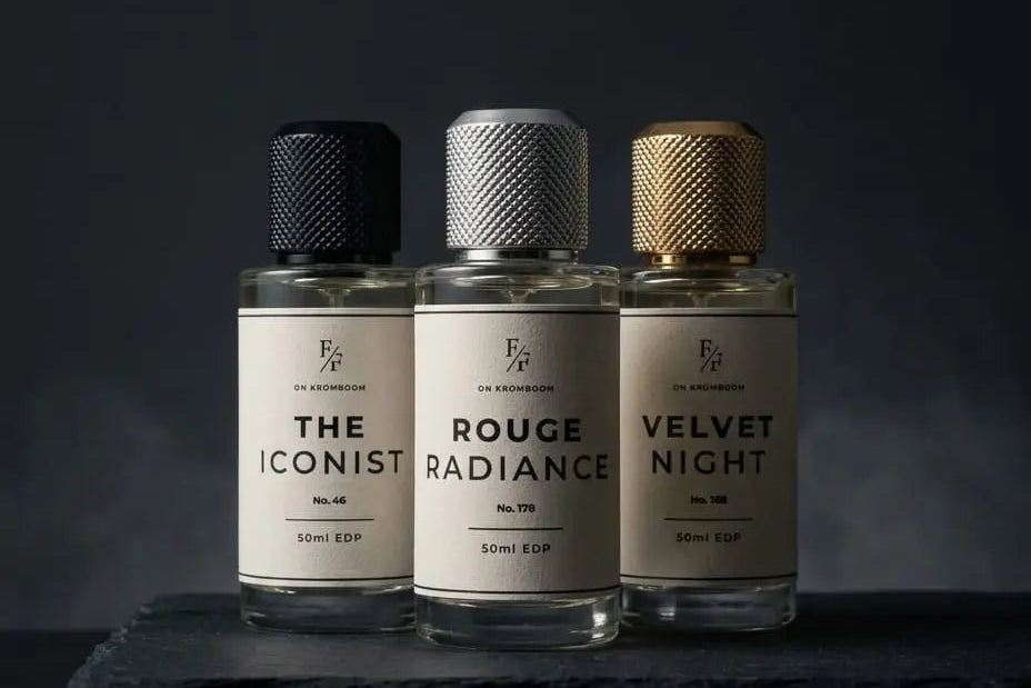 Three perfume bottles from the brand 'EP' lined up on a dark slate board against a dark background. The bottles are labeled 'THE ICONIST', 'ROUGE RADIANCE', and 'VELVET NIGHT' with textured black, silver, and gold caps.